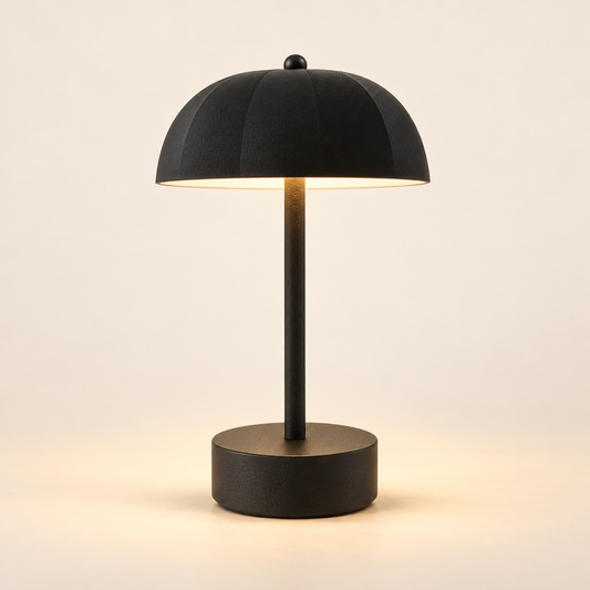 Milo rechargeable mushroom table lamp in black, softly illuminated against a warm ivory background.