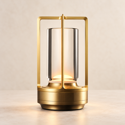 Atlas rechargeable outdoor lantern in gold, illuminated against a warm ivory background.